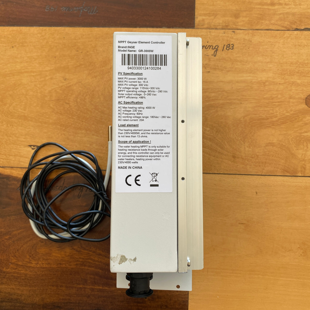 An HPPY Gray Element Controller electrical component with a white metal housing, a black cable coil, and a detailed product label, placed on a wooden surface.