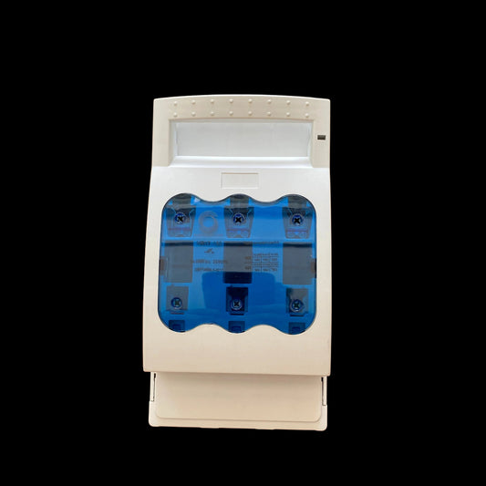 A white electrical fuse holder or circuit breaker component with a translucent blue window showing internal fuses, photographed on a wooden surface.